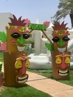 two wooden tiki statues in front of a sign that says aloha