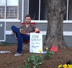 a man sitting in a chair next to a sign that reads run quietly i'm really hungry