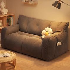 a stuffed animal sitting on top of a brown couch next to a wooden coffee table