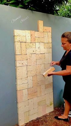 a woman standing next to a wall made out of wood planks and plywood