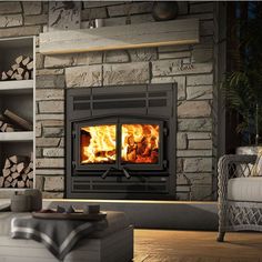 a living room filled with furniture and a fire place next to a stone wall covered in logs