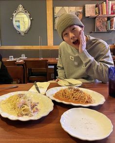 a man sitting at a table with two plates of food in front of him and the other plate has spaghetti on it