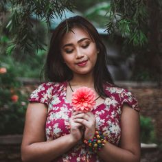 a woman holding a flower in her hands