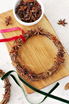 a wooden cutting board topped with a wreath and star anise