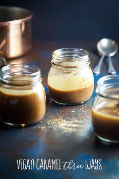 three jars filled with food sitting on top of a table next to two spoons