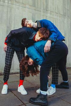 three people are hugging on the street with their heads touching each other's butts