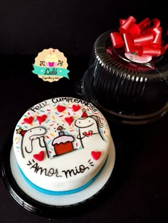 a decorated cake sitting on top of a table next to a container with red bows