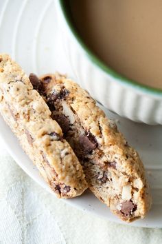 two cookies on a plate next to a cup of coffee