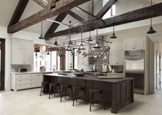 a large kitchen with an island and lots of lights hanging from the ceiling over it