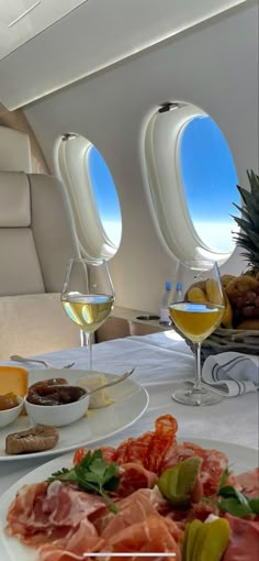 the table is set with food and wine for two people to enjoy on an airplane