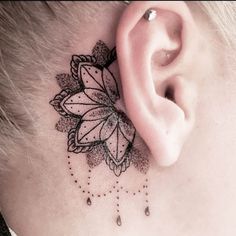 a close up of a person's neck with a flower behind the ear tattoo