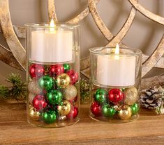 two glass candles with christmas ornaments in them