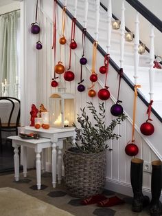 christmas decorations hanging from the banisters in a home's entryway, decorated with red and gold baubs