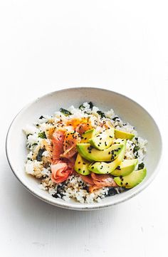 a bowl filled with rice and vegetables on top of a white countertop next to a fork