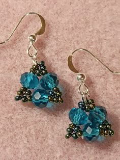 two pairs of earrings with blue and green beads hanging from them on a pink surface