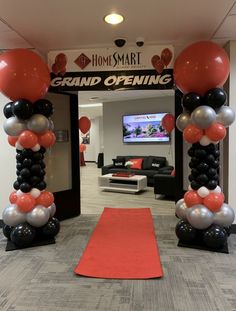 an entrance to a grand opening with balloons and streamers on the red carpet in front of it