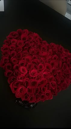 a bunch of red roses arranged in the shape of a heart on a black surface