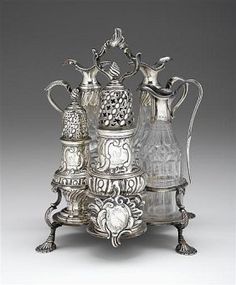 an ornately decorated silver coffee pot and two other items in the shape of a pyramid