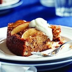 a piece of cake sitting on top of a white plate covered in whipped cream and apples