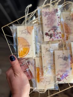 a person holding a tray filled with soaps on top of a wooden table next to an orange slice