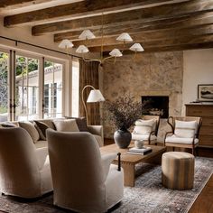 a living room filled with furniture and a fire place next to a stone wall covered in windows