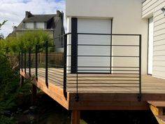 a house with a wooden deck and metal railings on the side of the house