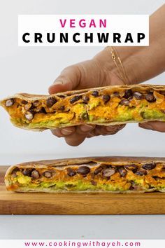 a person is holding up a sandwich that has been cut in half and placed on a cutting board