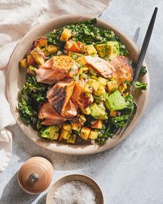 a salad with salmon, avocado and pineapple is served in a bowl