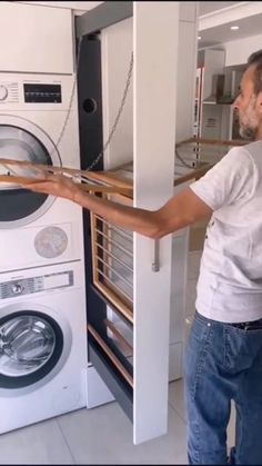 a man is opening the door to a washer and dryer