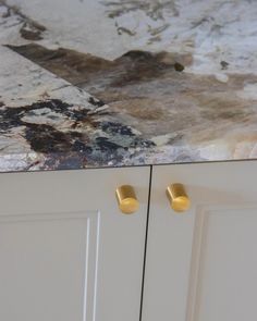 a marble counter top with gold handles and knobs on the cabinet doors in a kitchen