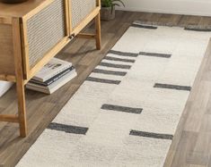 a white rug with black and grey stripes on the floor next to a wooden table