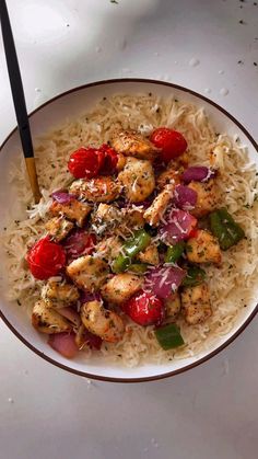 a white bowl filled with rice and meat on top of a table next to a fork