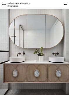 a bathroom with two sinks and a large round mirror