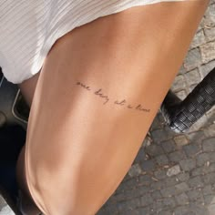 a woman with a tattoo on her leg that reads, one day at a time