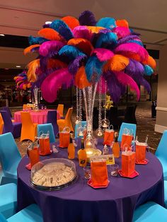 the table is decorated with bright colored feathers and place settings for guests to sit at