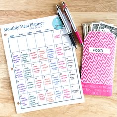 a calendar and pen sitting on top of a wooden table next to some cash notes