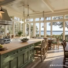 a kitchen with green cabinets and an island in the middle is surrounded by large windows