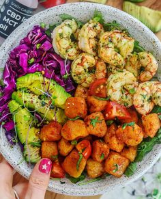 a bowl filled with shrimp, lettuce and tomatoes