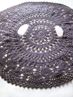 a crocheted doily with holes in the middle on a white table cloth