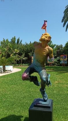 a statue of a man doing a handstand on top of a box in the grass