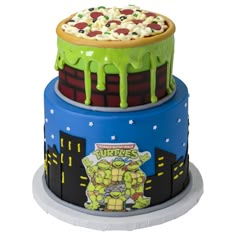 three tiered cake decorated with cartoon characters on it's sides and topped with green icing