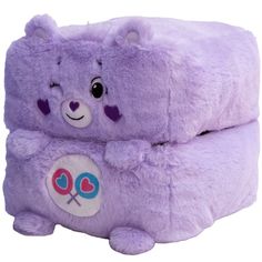 a purple teddy bear sitting on top of a pillow