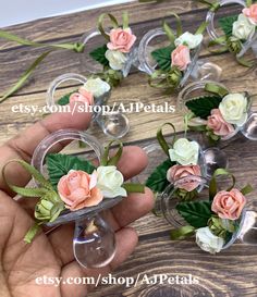 small glass vases with pink and white flowers in them are being held by someone's hand