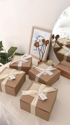 several brown boxes with white ribbons and bows are sitting on a table next to a mirror