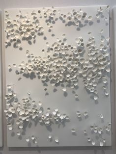 an art work with white circles on the wall and one piece of paper cut out to look like bubbles