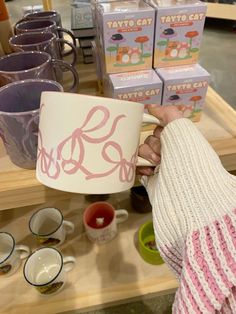 a person holding up a lamp in front of some cups