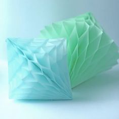 two blue and green folded paper pieces on a white surface