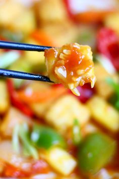 chopsticks holding up food that includes vegetables and tofu