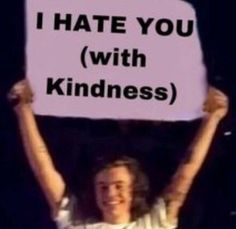 a man holding up a sign that says i hate you with kindness