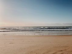 an empty beach with waves coming in from the ocean